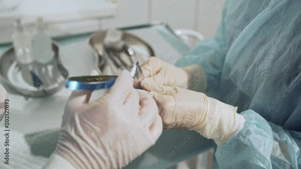 Surgical table with sterile medical instruments. The assistant gives the surgeon the scalpel blade. Closeup shot of doctors hands with surgical supplies. Concept of health, team work in the hospital. Surgical table with sterile medical instruments. The assistant gives the surgeon the scalpel blade. Closeup shot of doctors hands with surgical supplies. Concept of health, team work in the hospital.