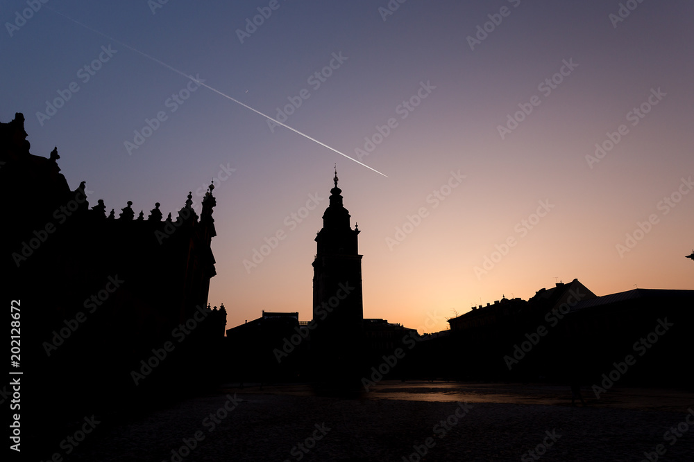 Silhouette of townhall clocktower in Market Square during beautiful coloured sunset, Krakow, Poland