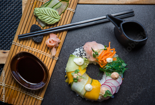 Vegan sushi donuts set with ginger, avocado, cucumber, chives served on stone slate. Sushi-food hybrids trend. high-end cuisine