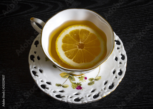 Lemon slice in fresh tea on a black background close-up.