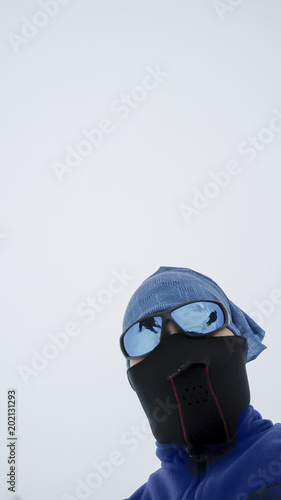 Hiker portrait high at the mountains with mask and glassess looks at the ultimate aim of his trip with fog at background photo