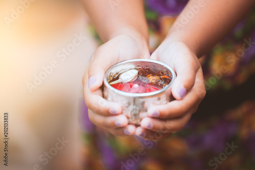 Asian little child girl holding a little bowl that have flower leaf in water for pouring on hands of elderly to respect grandparents for celebrate Songkran in new year