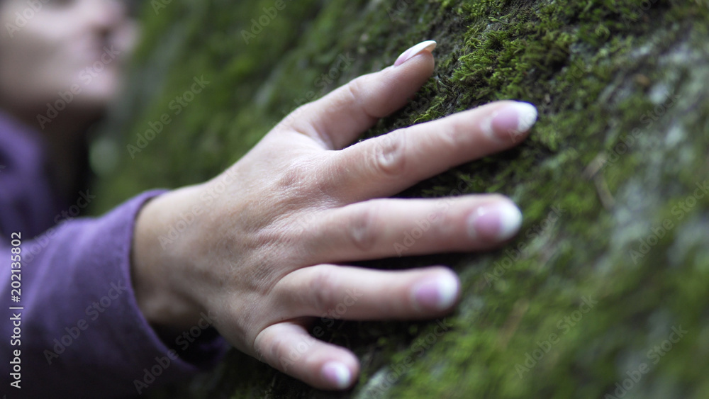 Cinematic view of thoughtfull woman in depression touching the stone moss in nature and exchanging emotion energy