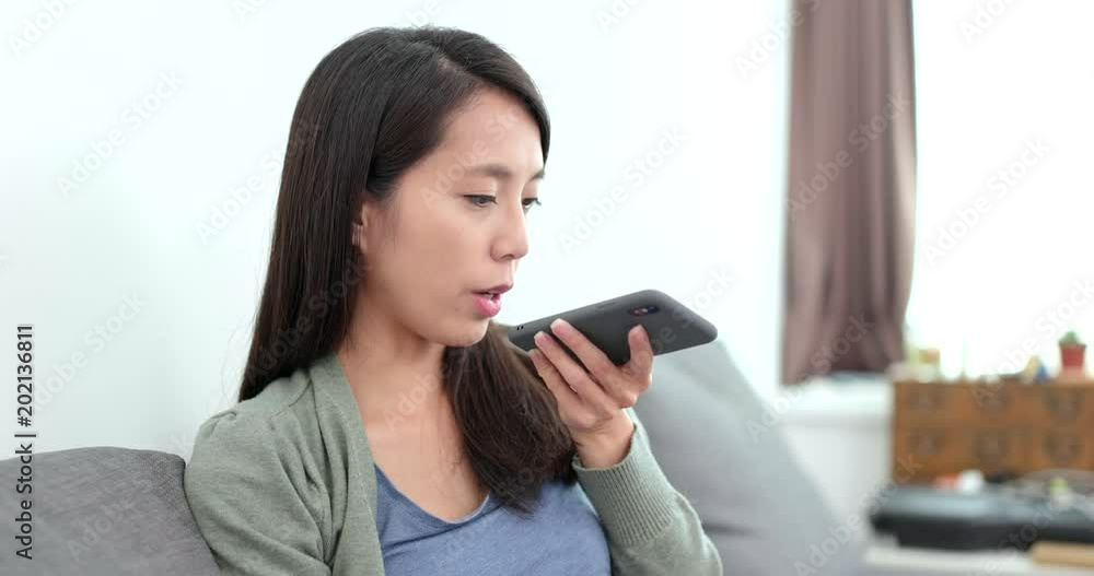Housewife sending audio message on cellphone at home Housewife sending audio message on cellphone at home