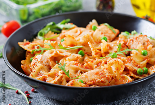 Farfalle pasta with chicken fillet, tomato sauce and green peas. Food menu