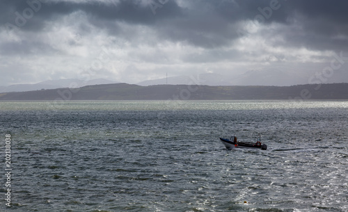 Lone fisherman heading out to sea on a stormy grey day