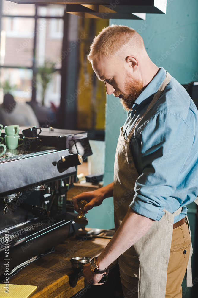 side view of young male barista using coffee machine side view of young male barista using coffee machine