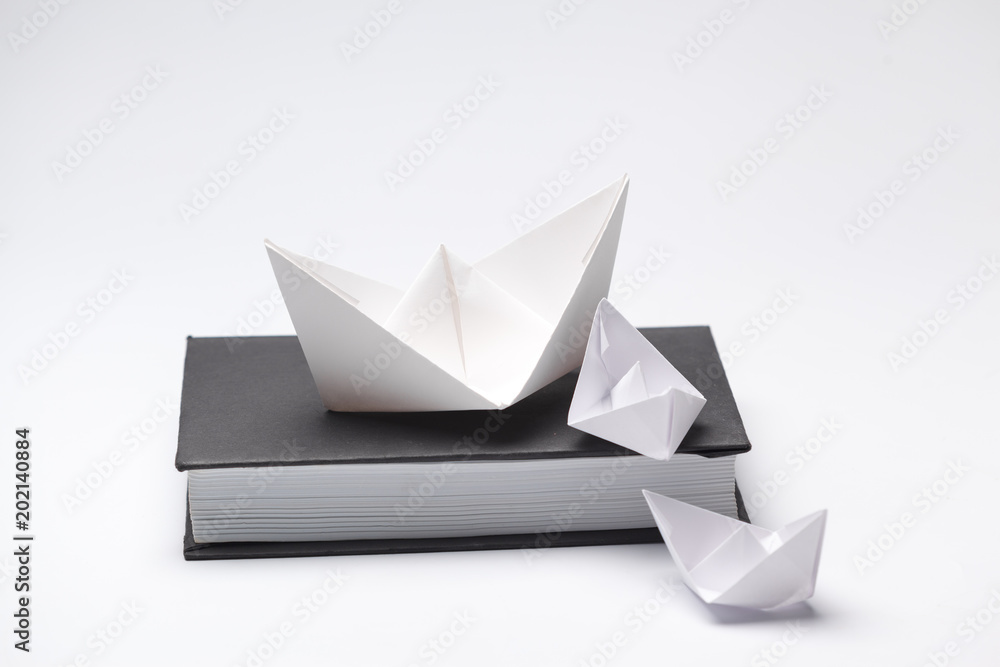 Origami paper boat on a book Origami paper boat on a book