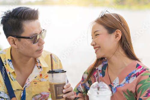 Asian couple drinking coffee and smileing on river background.