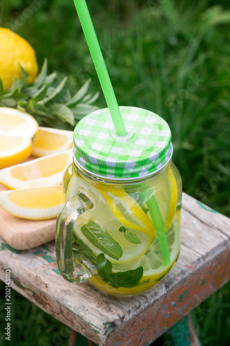 Homemade lemonade with mint and ice on a wooden bench in the garden. Rustic style. photo