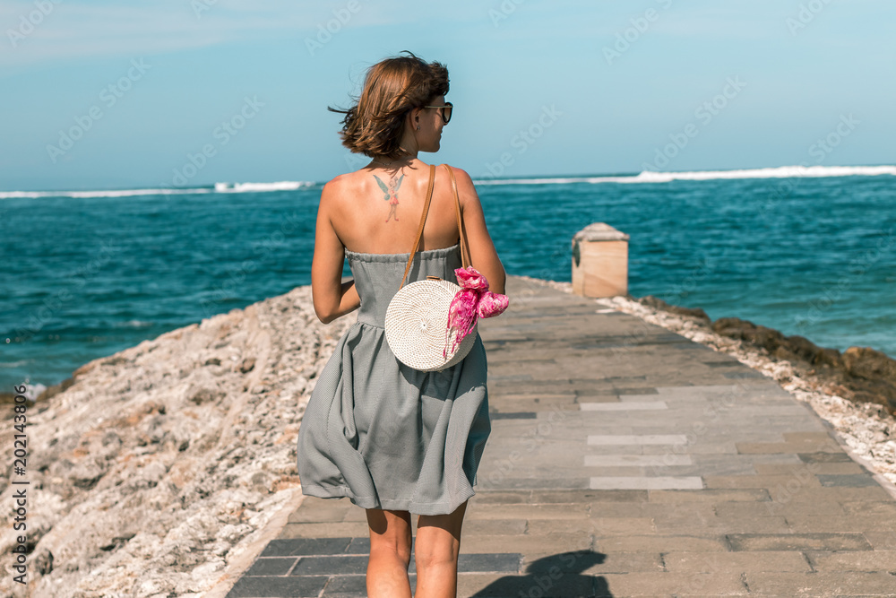 Woman with fashionable stylish white rattan bag and silk scarf outside. Tropical island of Bali, Indonesia. Rattan handbag and silk scarf. Woman with fashionable stylish white rattan bag and silk scarf outside. Tropical island of Bali, Indonesia. Rattan handbag and silk scarf.
