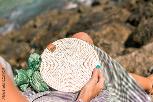 Woman hands with fashionable stylish white rattan bag and silk scarf outside. Tropical island of Bali, Indonesia. Rattan handbag and silk scarf. photo