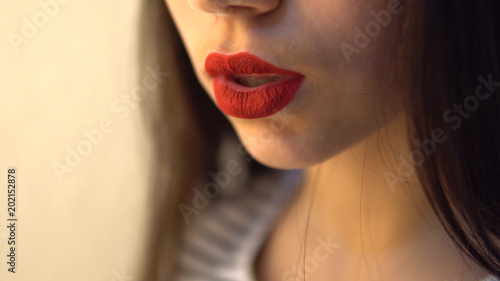 Beautiful girl apply red lipstick rouge and gently look at camera