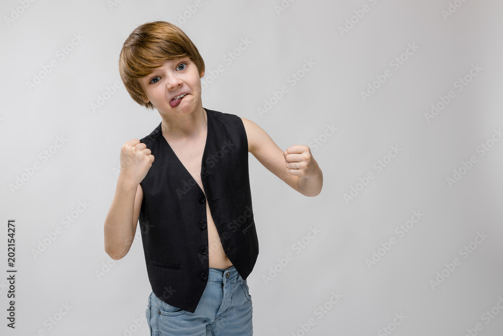 Portrait of adorable surprised little boy standing in studio holding his hands in fist on grey background Portrait of adorable surprised little boy standing in studio holding his hands in fist on grey background