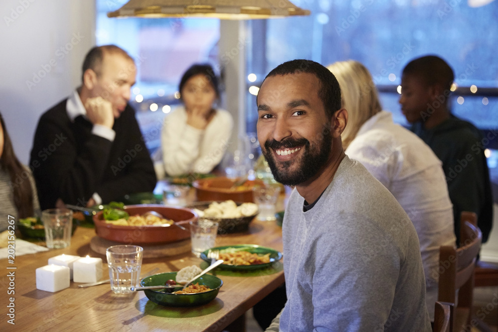 Portrait of smiling father sitting with family during meal at table Portrait of smiling father sitting with family during meal at table