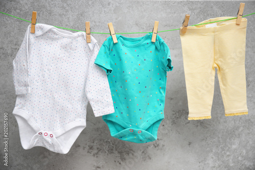 Baby clothes hanging on washing line against gray background photo