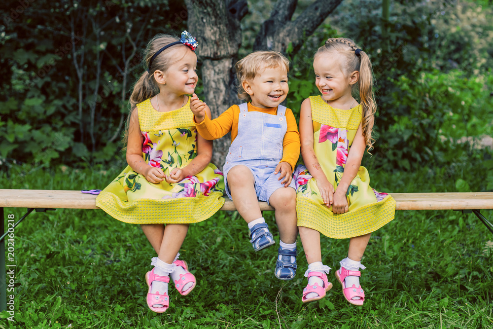 Fototapeta premium Happy children boy and two twin sisters are having fun in the park in the summer