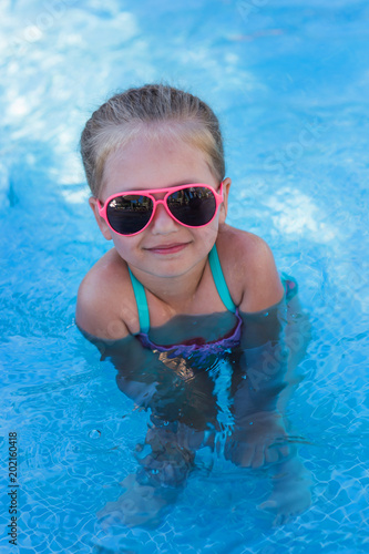 cute little funny girl in sunglasses on vacation at the pool
