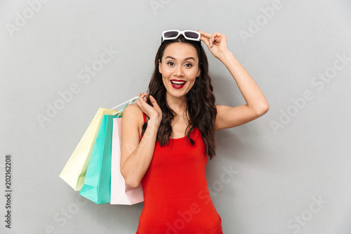 Fotografie Surprised happy brunette woman in casual clothes takes off sunglasses