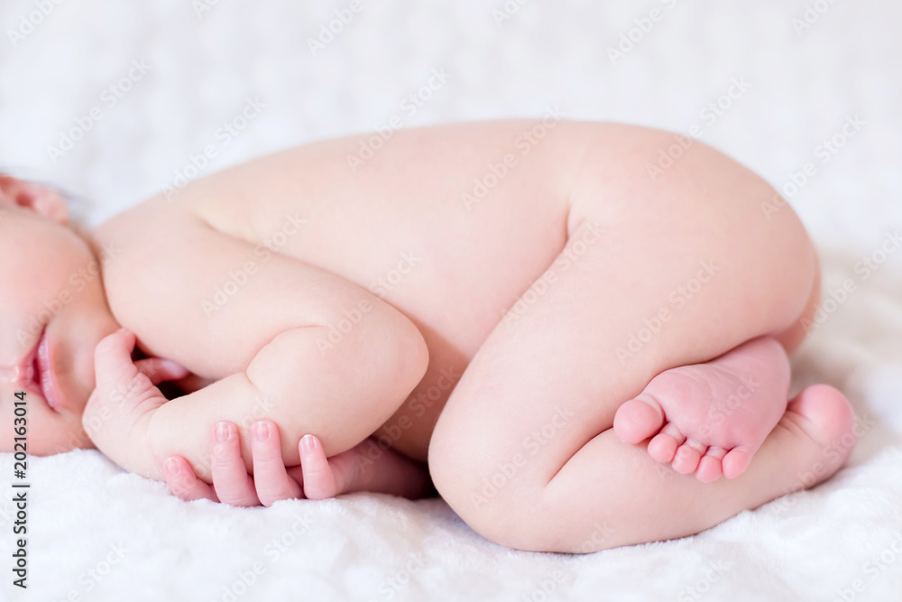 Nouveau-né endormi nu sur une couverture blanche