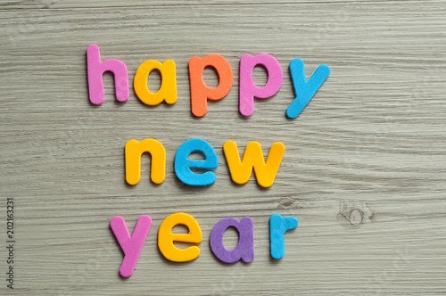 Happy new year in colorful letters on a wooden background