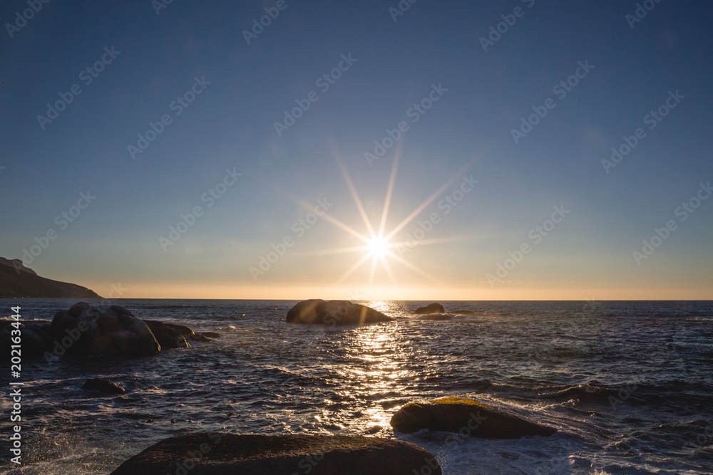Obraz premium Sunset over the water with rocks