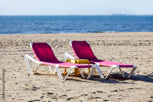 beach chaise lounge sea sand sky horizon signs advertising black blue pink red