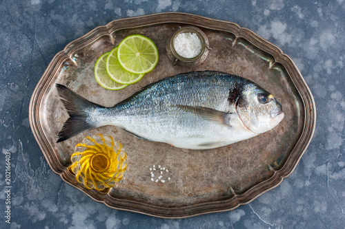 Fresh raw Dorado fish on a metal tray with ingredients for cooking, top view, horizontal