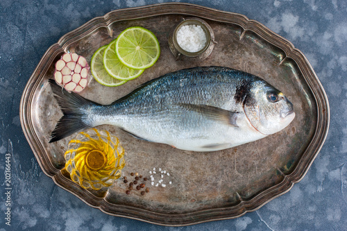 Fresh raw Dorado fish on a metal tray with ingredients for cooking, top view, horizontal