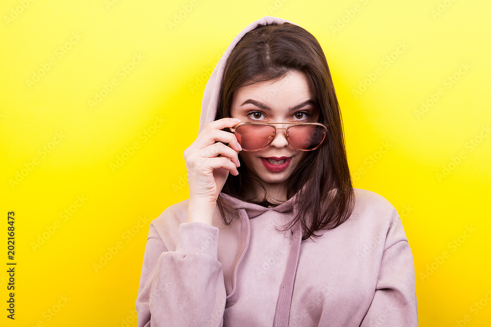Sexy woman wearing a hood and eyeglasses on yellow background Sexy woman wearing a hood and eyeglasses on yellow background