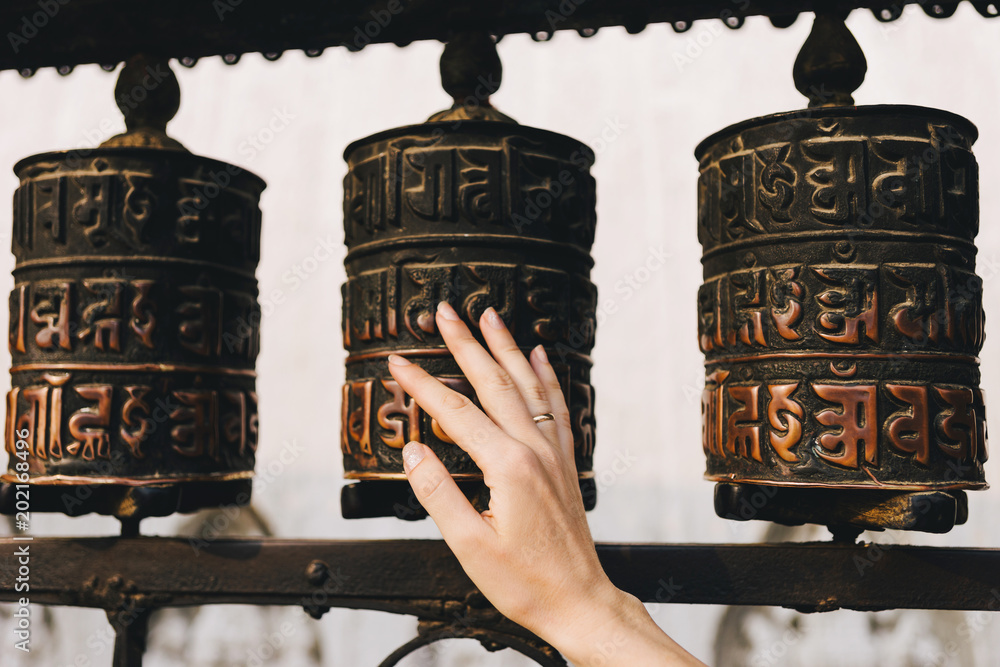 Buddhist prayer drums with closeup mantras.The female hand touches the