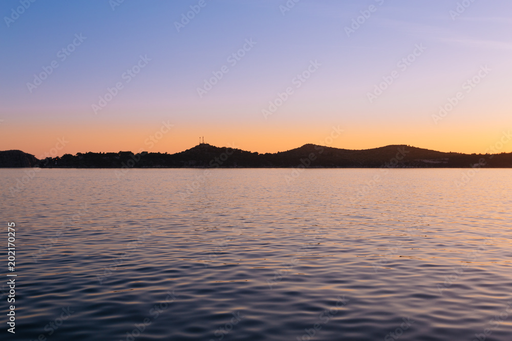 Minimalistisch - Sonnenuntergang über dem Meer mit Bergsilhouette