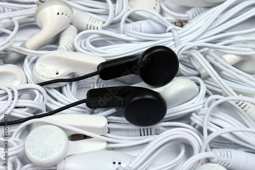 Black headphones on pile of white earphones