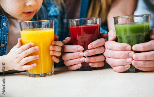Family holding a glass of juice in hands.