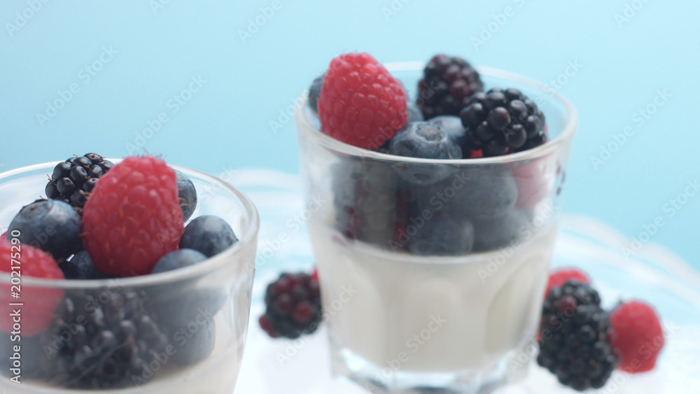 glasses with greek yogurt with berries Minimalism food on blue background. Panna cotta with strawberry raspberry, blueberry glasses with greek yogurt with berries Minimalism food on blue background. Panna cotta with strawberry raspberry, blueberry