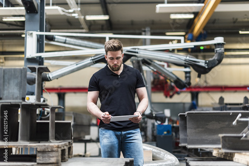 Man with tablet standing on factory shop floor