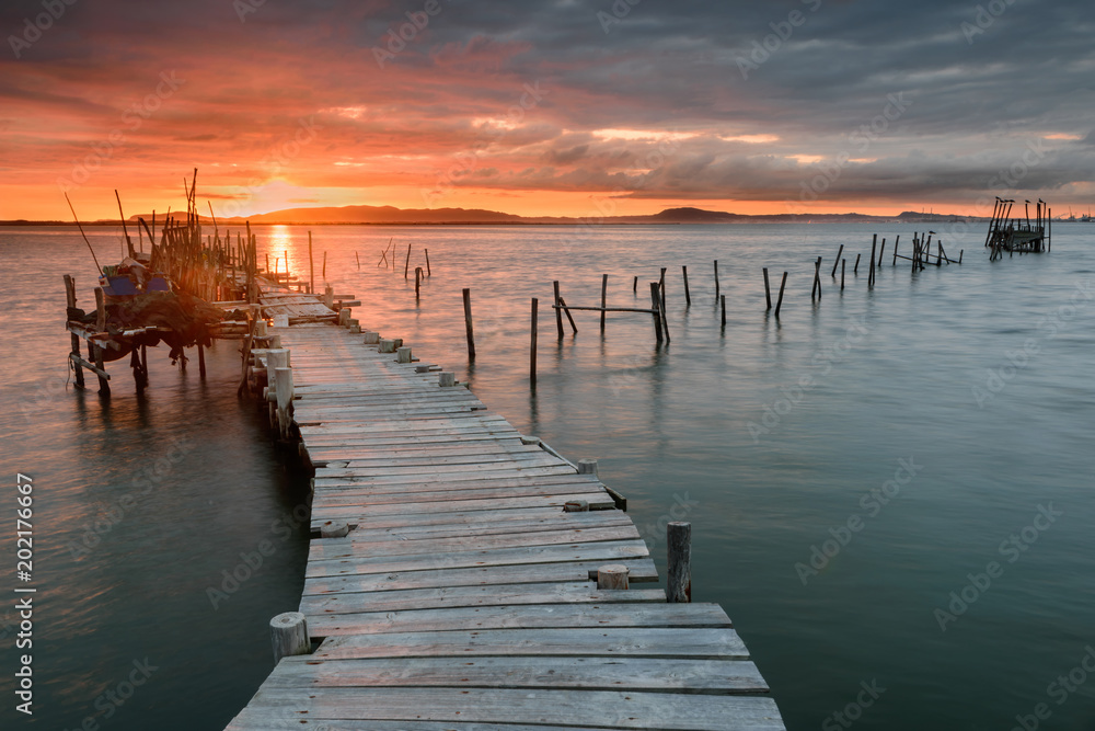 Sunset landscape of artisanal fishing boats in the old wooden pier. Carrasqueira is a tourist destination for visitors to the coast of Alentejo near Lisbon.