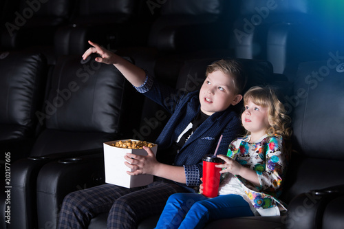 Brother and sister sitting at the cinema, watching a film and eating popcorn. movie theater.