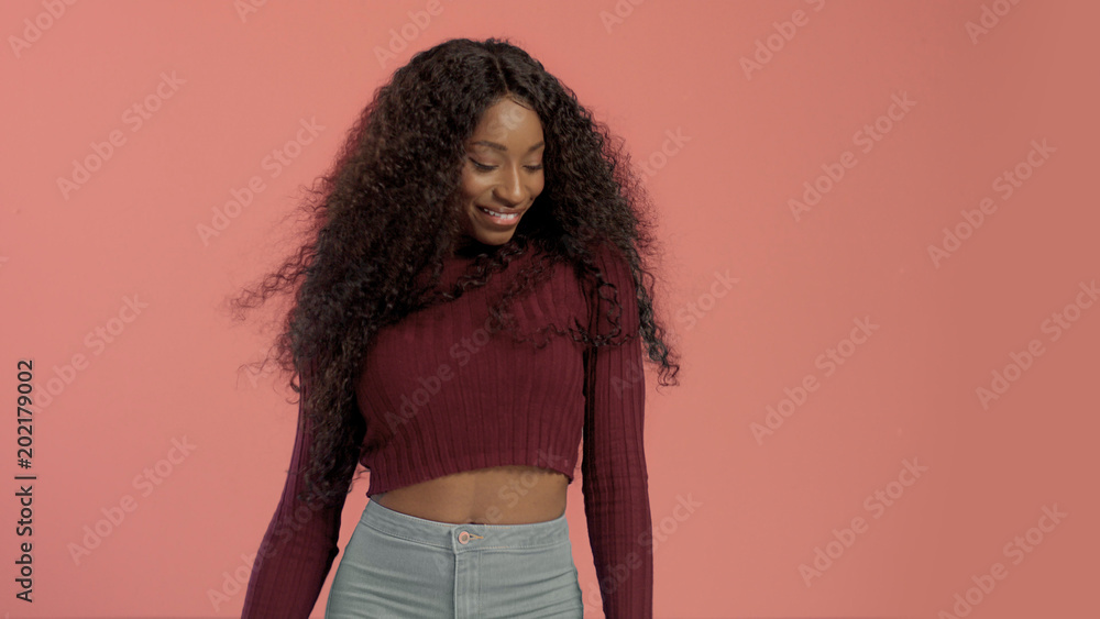 Beauty mixed race african american woman with hair blowed in air smiling at camera dancing On pink background. Beauty mixed race african american woman with hair blowed in air smiling at camera dancing On pink background.