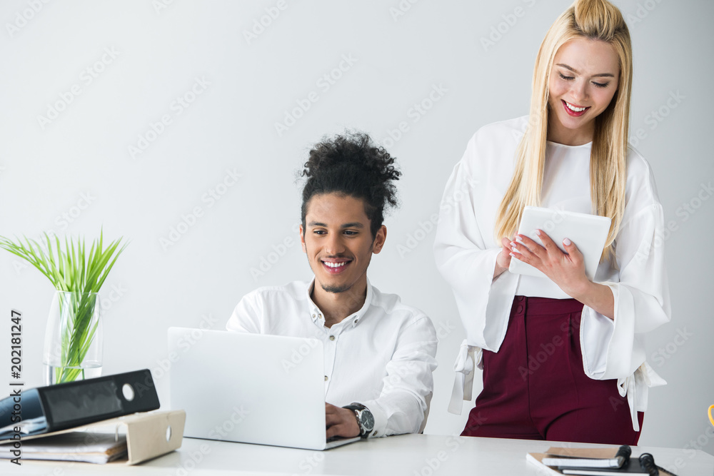 smiling young business people working with digital devices in office smiling young business people working with digital devices in office