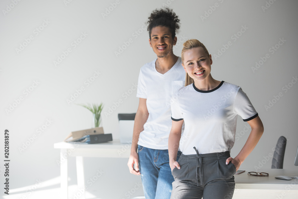cheerful young multiethnic colleagues smiling at camera while standing together in office cheerful young multiethnic colleagues smiling at camera while standing together in office