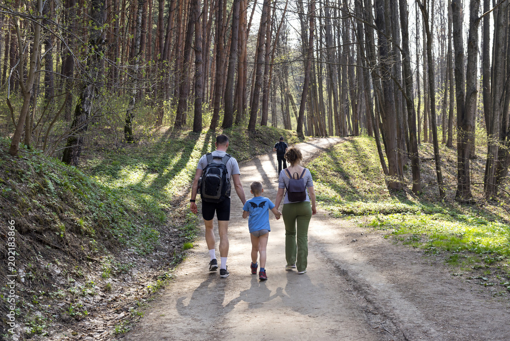 family walks in the woods, mom, dad and son are among the trees
