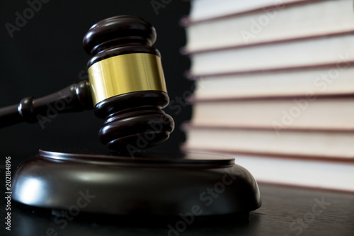 Judge gavel beside pile of books on wooden background