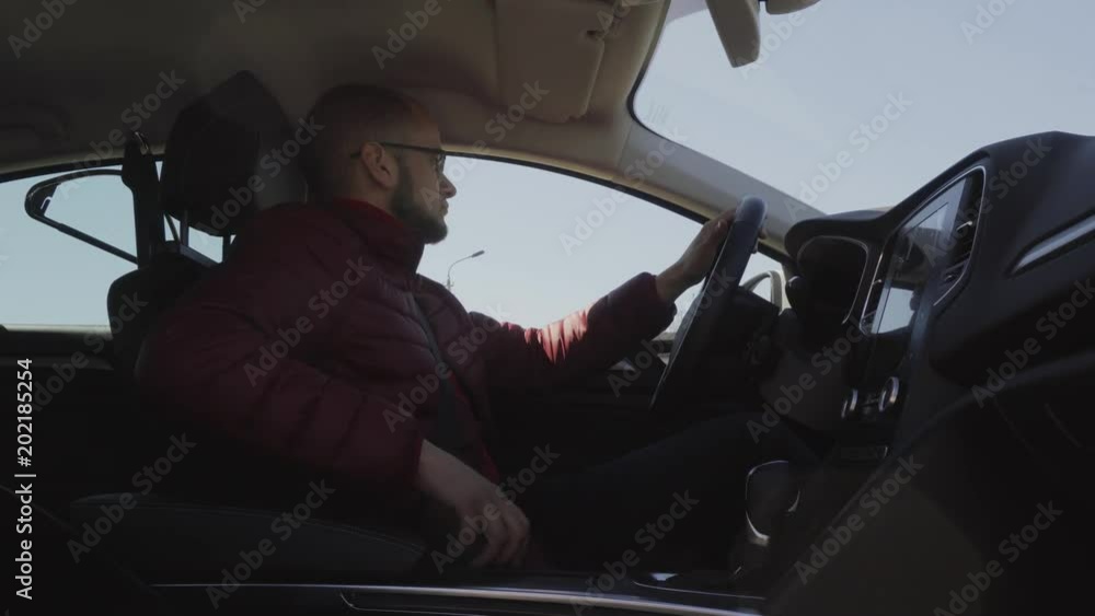 A young male businessman is getting out of a new car. He unfastens the seat belt. A successful guy.4k A young male businessman is getting out of a new car. He unfastens the seat belt. A successful guy.4k