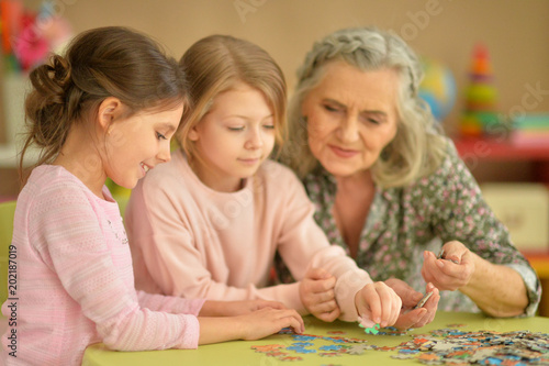  little girls with grandmother collecting puzzles