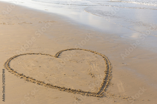 Heart drawn on a sand beach with the sea in the morning.