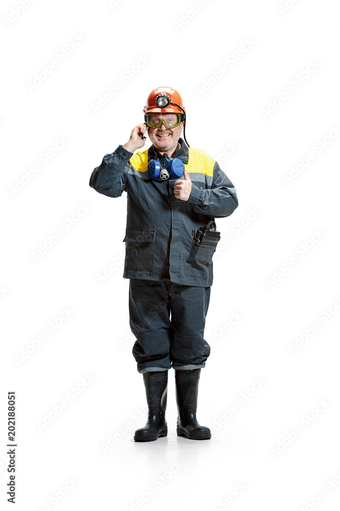 The studio shot of happy senior bearded male miner standing at the camera with smartphone on a white background. The studio shot of happy senior bearded male miner standing at the camera with smartphone on a white background.