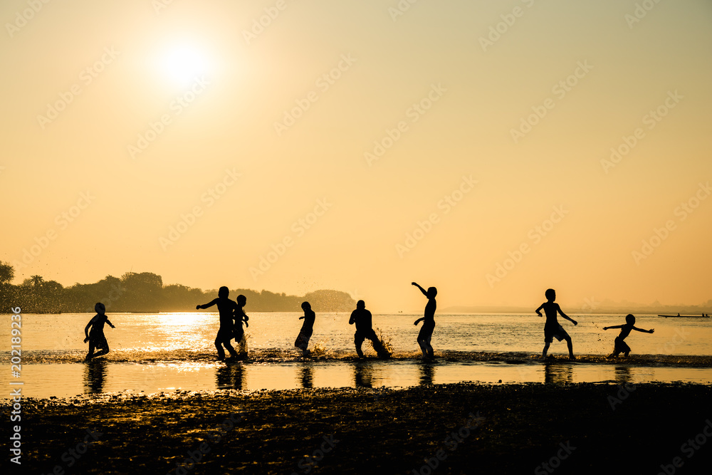 Silhouette of children playing water with friend Silhouette of children playing water with friend