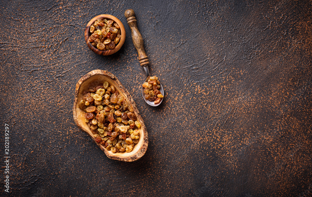 Raisins in wooden bowl on rusty background Raisins in wooden bowl on rusty background