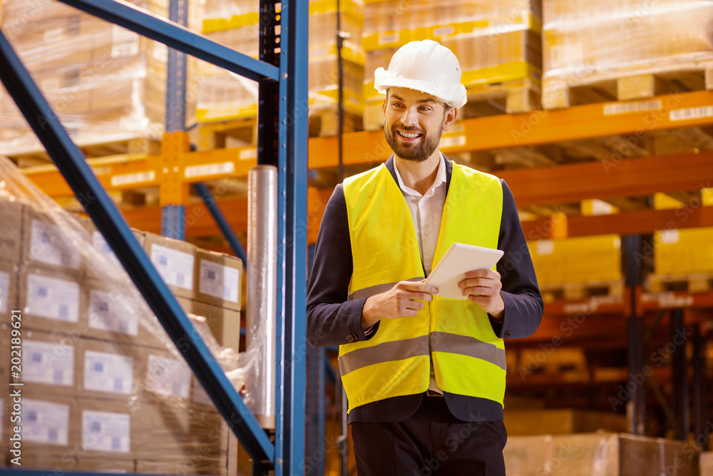 Delivery service. Smart cheerful man wearing uniform while controlling the delivery service Delivery service. Smart cheerful man wearing uniform while controlling the delivery service